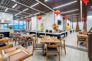 A modern restaurant with wooden tables and chairs, a central bar area, and red lanterns. - Emerald Bay Hotel & Spa Nha Trang (Nha Trang)