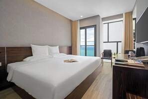 A hotel room with a large bed, a desk with a chair, a television, and a view of the ocean. - Emerald Bay Hotel & Spa Nha Trang (Nha Trang)