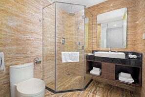 A modern bathroom with a glass-enclosed shower, a white toilet, and a vanity with a mirror and sink. - Emerald Bay Hotel & Spa Nha Trang (Nha Trang)