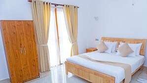 A bedroom with a wooden bed, beige curtains, and a wooden wardrobe. - Santon Resort & Spa (Kahandamodara)