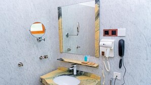 A bathroom with a marble sink, two mirrors, a towel rack, a soap dispenser, a hairdryer, and a telephone. - Santon Resort & Spa (Kahandamodara)