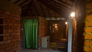 A rustic room with brick walls, a green curtain, a small white cabinet, and a bench. - Santon Resort & Spa (Kahandamodara)