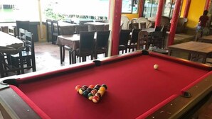 A pool table with a red felt surface and a set of billiard balls arranged in a triangle formation. - Jaya Hostel - Adults Only (Ko Pha-ngan)
