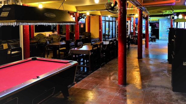 A billiards table in a dimly lit room with red pillars and a pool table. - Jaya Hostel - Adults Only (Ko Pha-ngan)