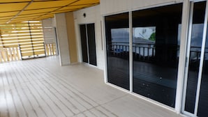 A spacious balcony with a wooden floor and large sliding glass doors leading to an outdoor area. - Jaya Hostel - Adults Only (Ko Pha-ngan)