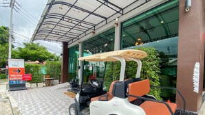 A golf cart parked in front of a building with a sign indicating 'East Inns' and a welcome message. - East Inn 15 Rayong (Rayong)
