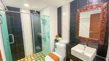 A bathroom with a glass-enclosed shower, a white toilet, a sink, and a mirror with an ornate frame.