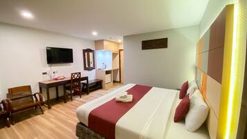 A hotel room with a bed, a desk, a chair, a television, and a bathroom.