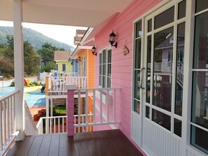 A colorful building with a wooden deck and a pool. - Bunny Hill Resort (Sattahip)