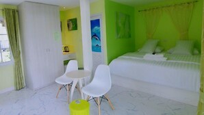 Una habitación con cama, escritorio, dos sillas y un taburete pequeño.