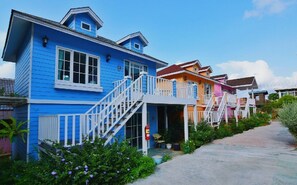 A row of colorful houses with white railings and steps leading to the entrance. - Bunny Hill Resort (Sattahip)