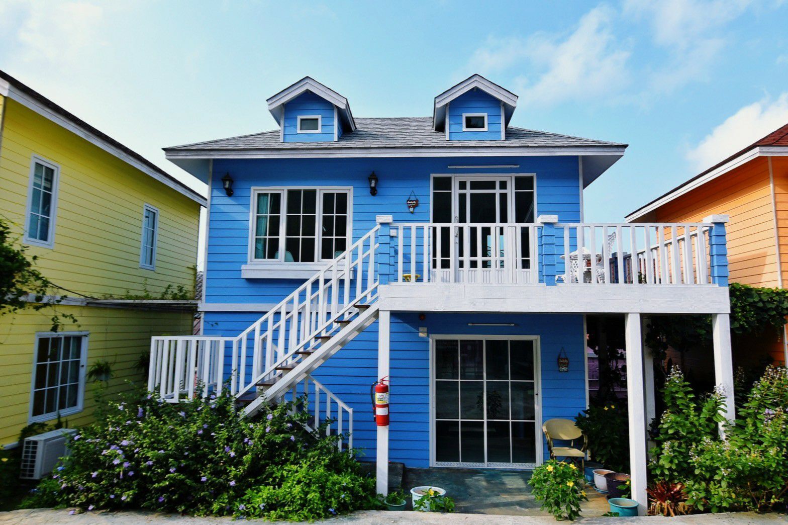 A two-story building with a balcony, a fire hydrant, and a small porch area.