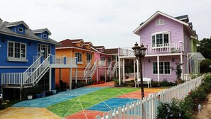 Un barrio residencial colorido con casas que tienen cercas blancas y un sendero pavimentado.