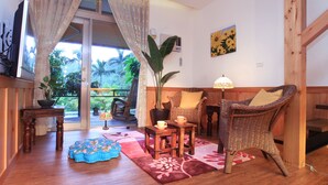 A cozy living room with a wooden floor, a wicker chair, a small table with cups, a potted plant, and a view of the outdoors. - Country Grange (Yuanshan)