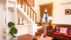 A living room with a wooden staircase, a sofa, a coffee table, and a potted plant. - Country Grange (Yuanshan)