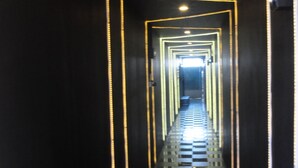 A long, narrow hallway with reflective black walls and a checkered floor. - Nay Chi Linn Hotel (Pathein)