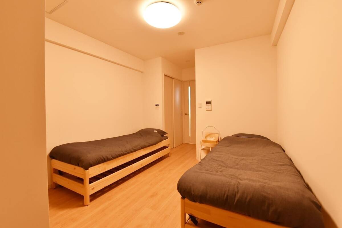 Una habitación pequeña y estrecha con dos camas individuales y una mesita.