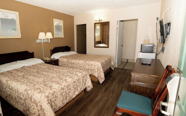 A hotel room with two beds, a desk, a chair, a TV, and a mirror.