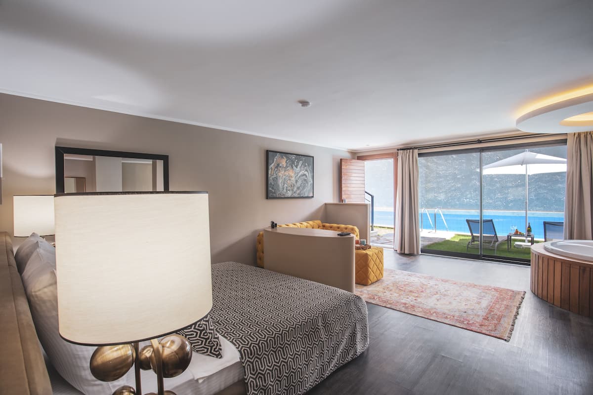 Una habitación de hotel moderna con una cama, un escritorio, una zona de estar y un balcón con vistas al mar.