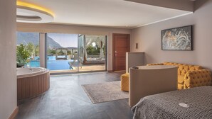 Un hotel moderno con una cama grande, una zona de estar, una bañera y vistas a una piscina y montañas.