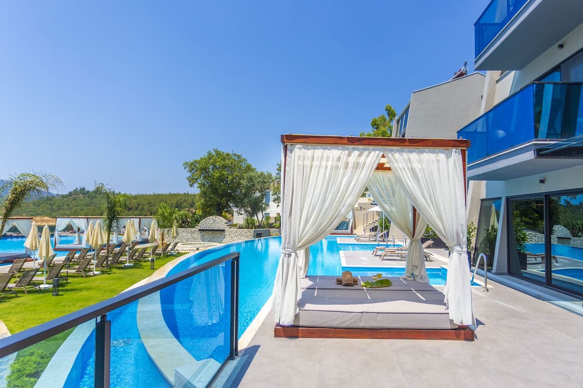 Zona junto a la piscina con una pérgola, sillones de descanso y vistas a la piscina.