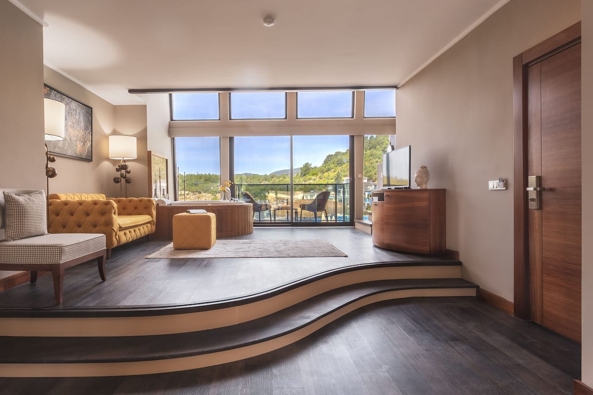 Una sala de estar moderna con una escalera curva, un sofá, una mesa de centro y vistas al exterior.