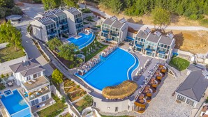 Un moderno resort con múltiples piscinas, tumbonas y una amplia piscina central.