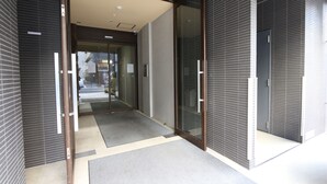 A modern building entrance with a glass door, a metal handle, and a mat on the floor. - Elizabeth Garden Shinsaibashi (Osaka)