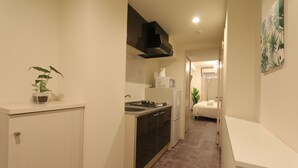 A compact kitchen with a microwave, stove, and cabinets. - Elizabeth Garden Shinsaibashi (Osaka)