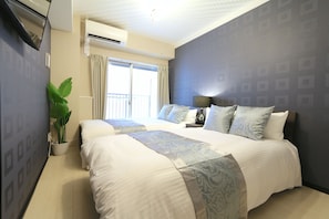 Ein Hotelzimmer mit einem großen Bett, einer Zimmerpflanze und einem Balkon mit Vorhängen.