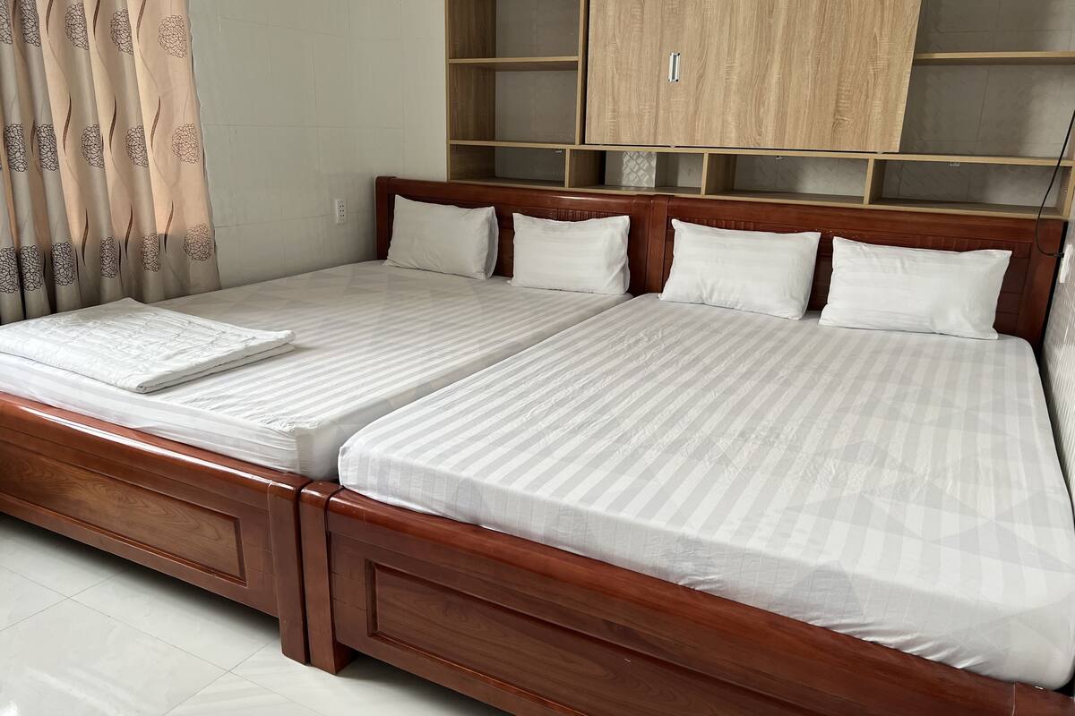 A double bed with a wooden frame and headboard, two pillows, and a white bedspread.