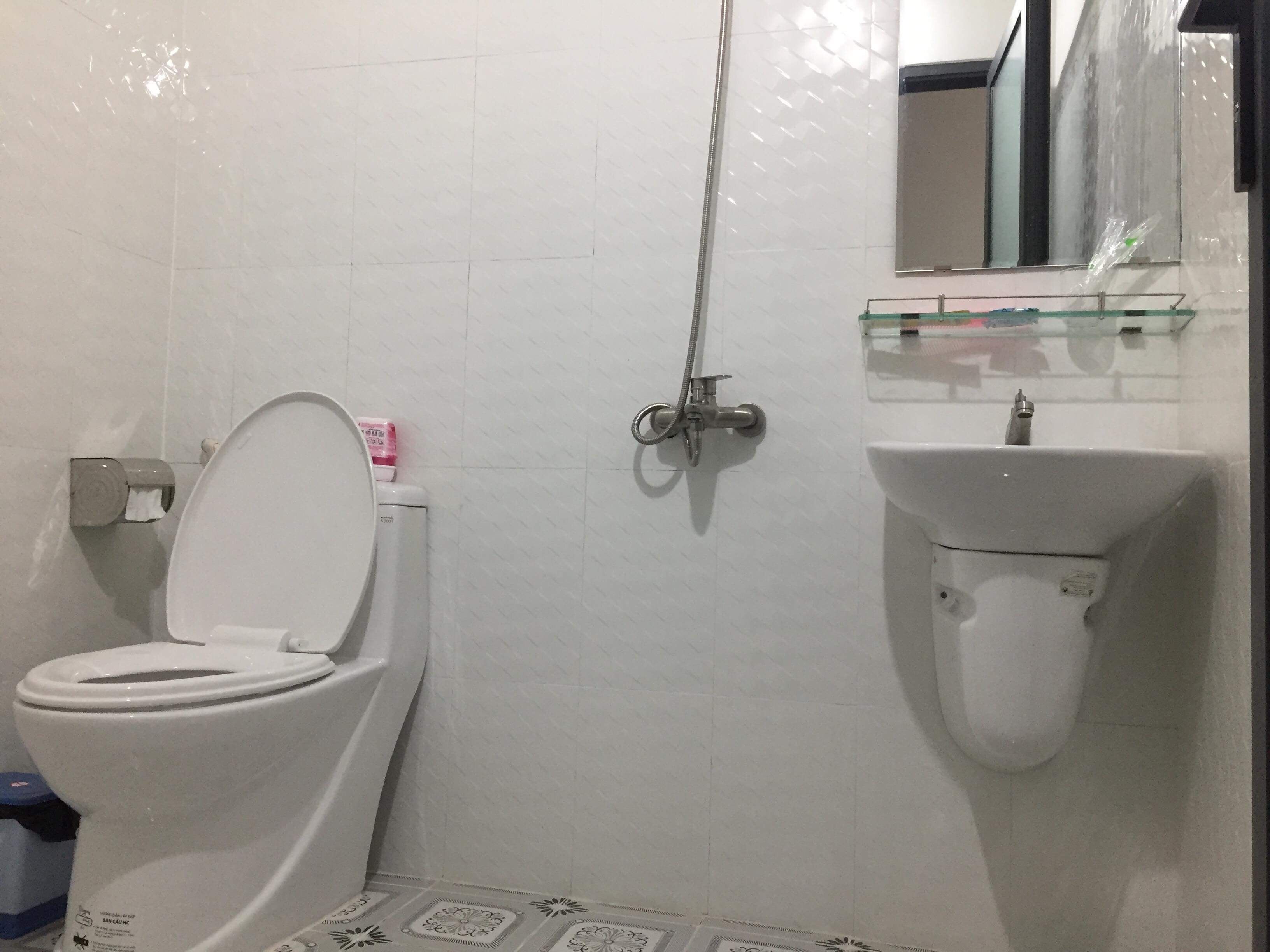 A bathroom with a toilet, a shower, and a sink.