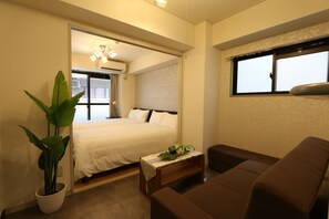 A bedroom with a bed, bedside table, and a potted plant. - Elizabeth Garden II (Osaka)