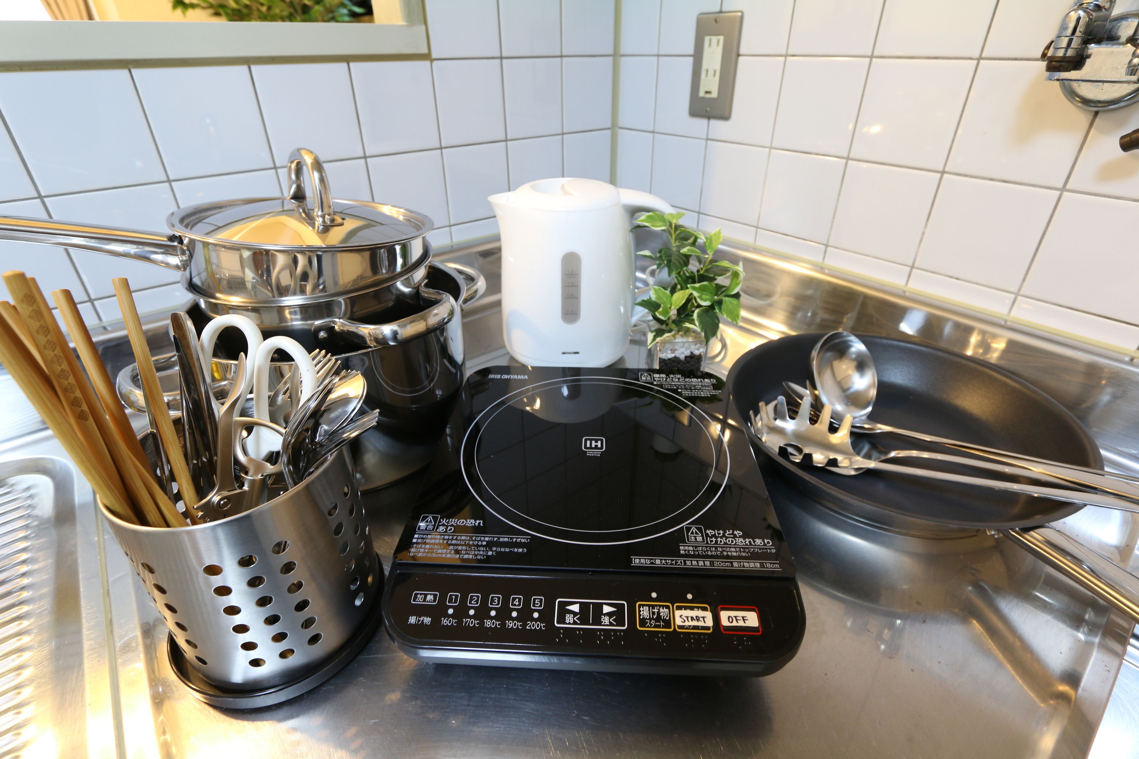 A kitchen with a stove, pots, a kettle, and various utensils.