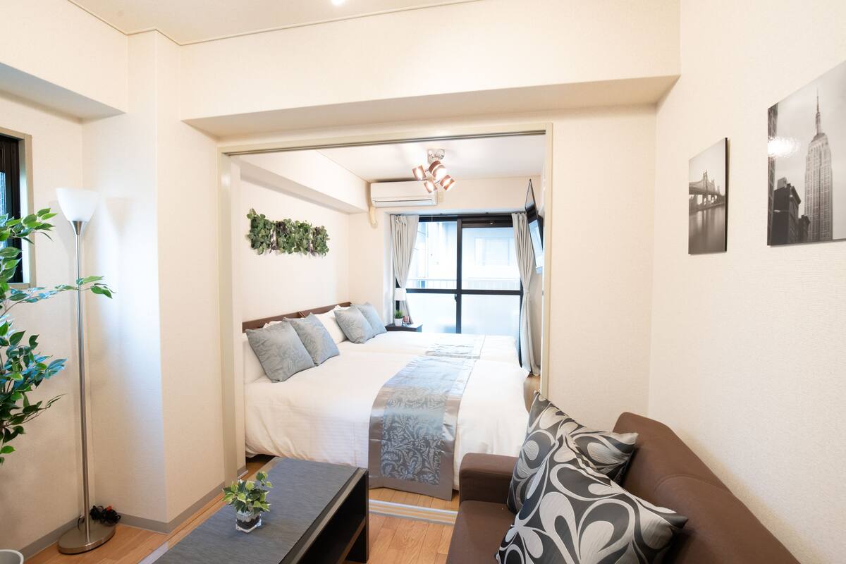 Une chambre d’hôtel moderne, dotée d’un grand lit, d’un canapé, d’un bureau et offrant une vue sur la ville par la fenêtre.