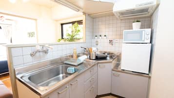 Een koelkast, een magnetron, een kookplaat, kookgerei, borden en bestek