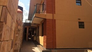 A narrow alleyway between buildings with a stone wall on the left and a building with a balcony on the right. - Bunyonyi Inn Hotel (Kampala)