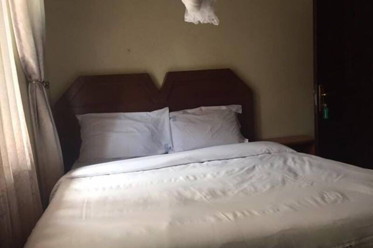 A bed with white bedding and a wooden headboard in a dimly lit room.