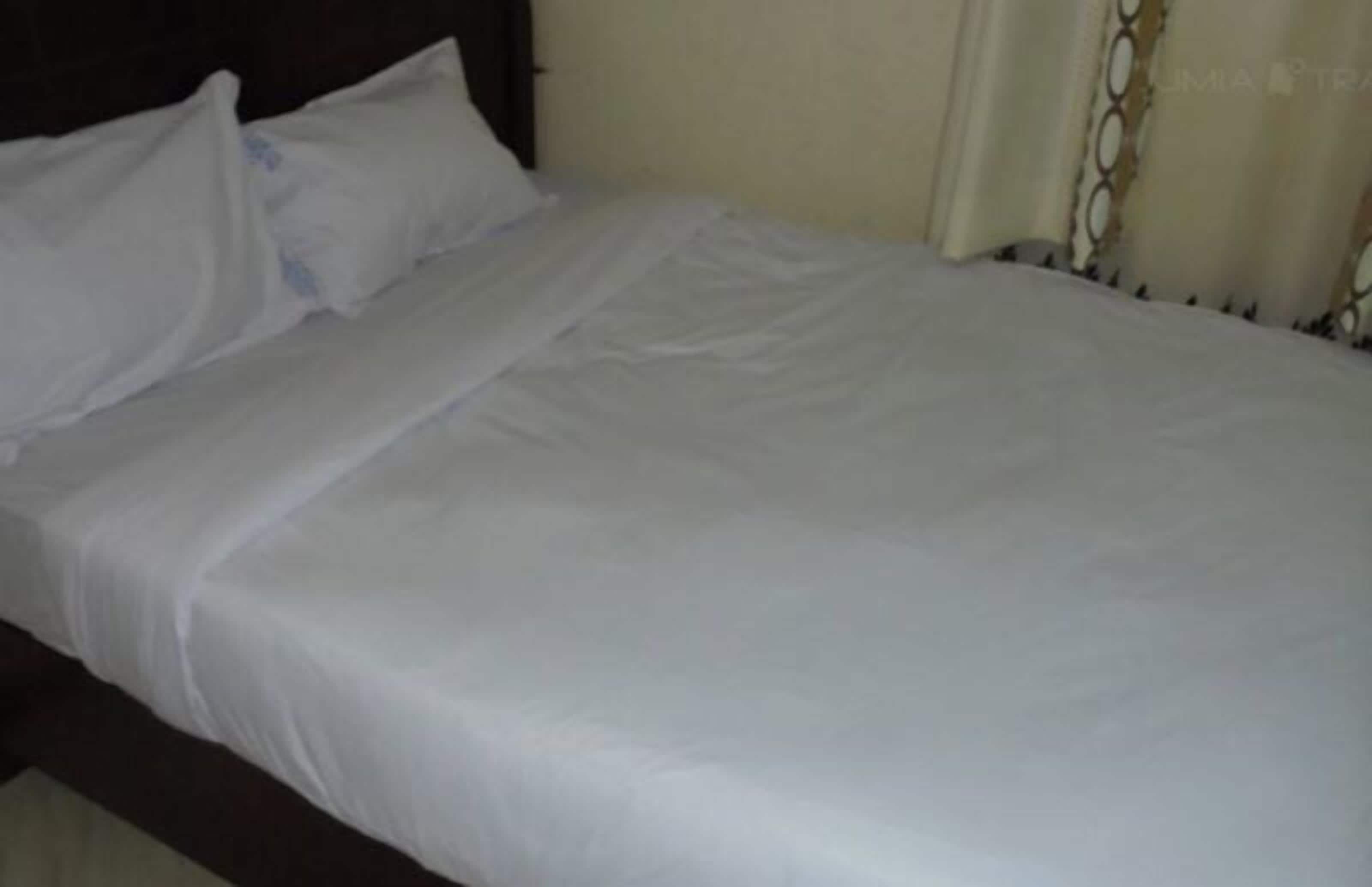 Una cama con ropa blanca y un cabecero oscuro.