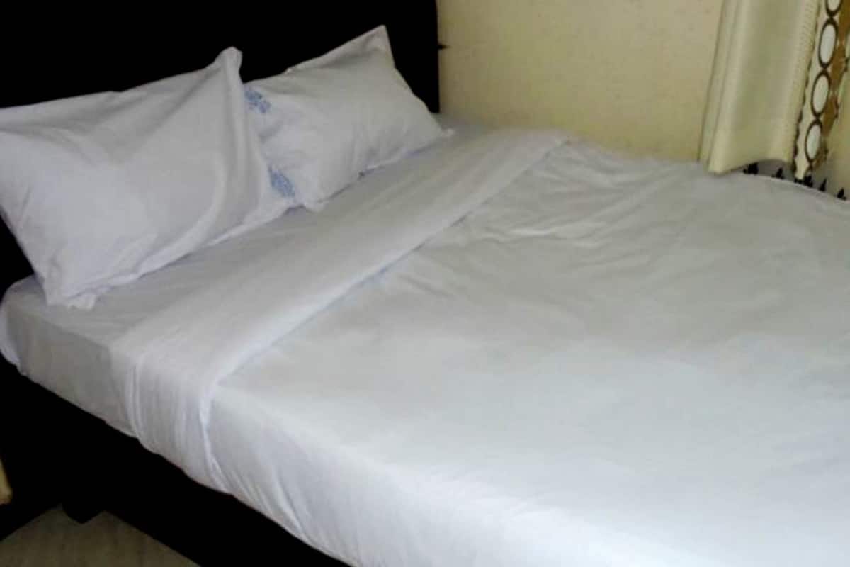 A bed with white bedding, a black headboard, and a plain wall.