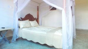 A single bed with a canopy, a wooden headboard, and a bedside table. - Japs Motel Mbarara (Mbarara)