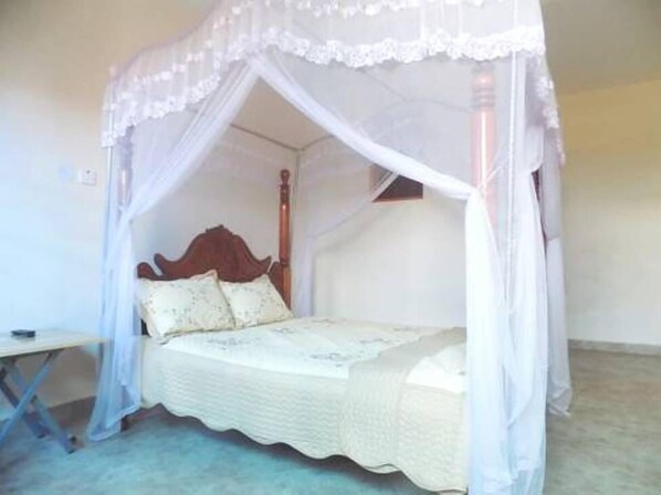 A single bed with a canopy, a wooden headboard, and a bedside table.