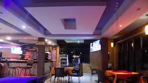 A restaurant with tables and chairs, a bar area, and a television screen. - Japs Motel Mbarara (Mbarara)