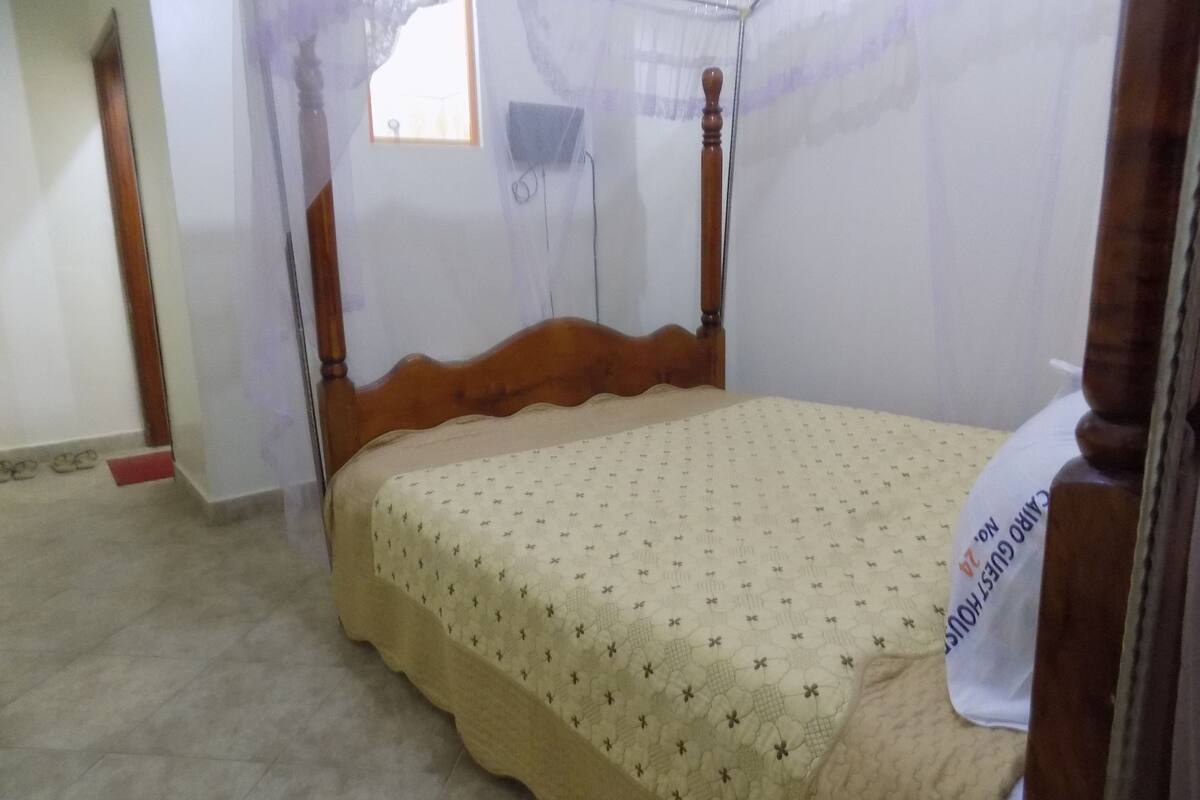 Un lit simple avec un cadre en bois et un baldaquin.