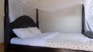 A four-poster bed with a canopy, white bedding, and floral-patterned pillows.