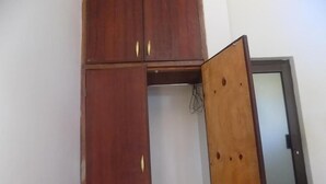 A wooden wardrobe with a mirrored door and a small shelf.