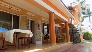 A hotel with a covered outdoor seating area, a staircase, and a door labeled "ROOM".