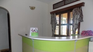 A reception desk with a green and white color scheme, a framed picture above it, and a window with curtains.