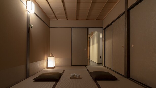 A traditional Japanese room with tatami flooring, a shoji screen door, and a small bedside table with a lamp. - Mimari (Kanazawa)