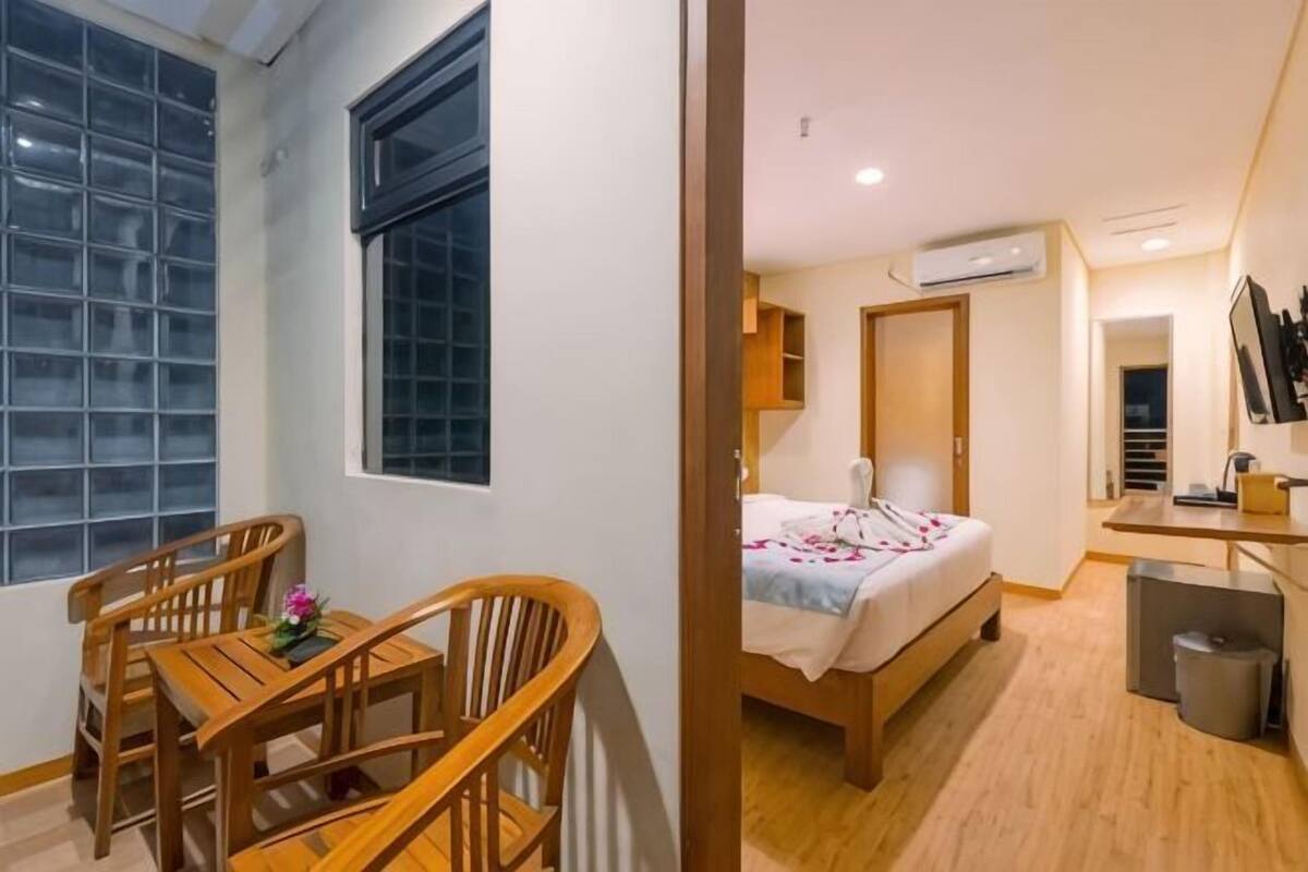 Quarto com cama, escrivaninha, cadeira e janela.